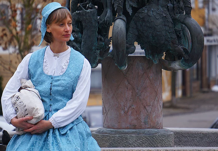 Lara erzählt Geschichte und Geschichten bei einer der Stationen, dem Regenstaufer Sagenbrunnen am Marktplatz.