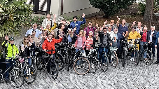 Winkende Menschen mit Fahrrädern für die Aktion Stadtradeln