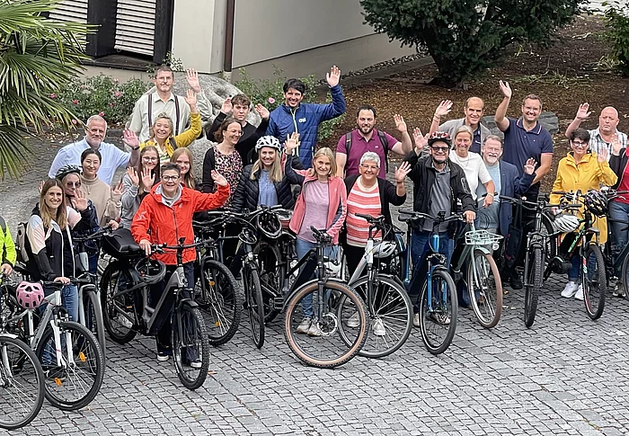 Winkende Menschen mit Fahrrädern für die Aktion Stadtradeln