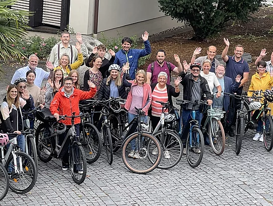 Winkende Menschen mit Fahrrädern für die Aktion Stadtradeln
